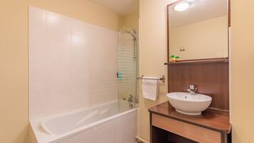 A bathroom with a bathtub, a glass-enclosed shower, and a wooden vanity with a sink.