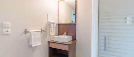 Un baño moderno con tocador de madera, un lavabo blanco y un espejo.
