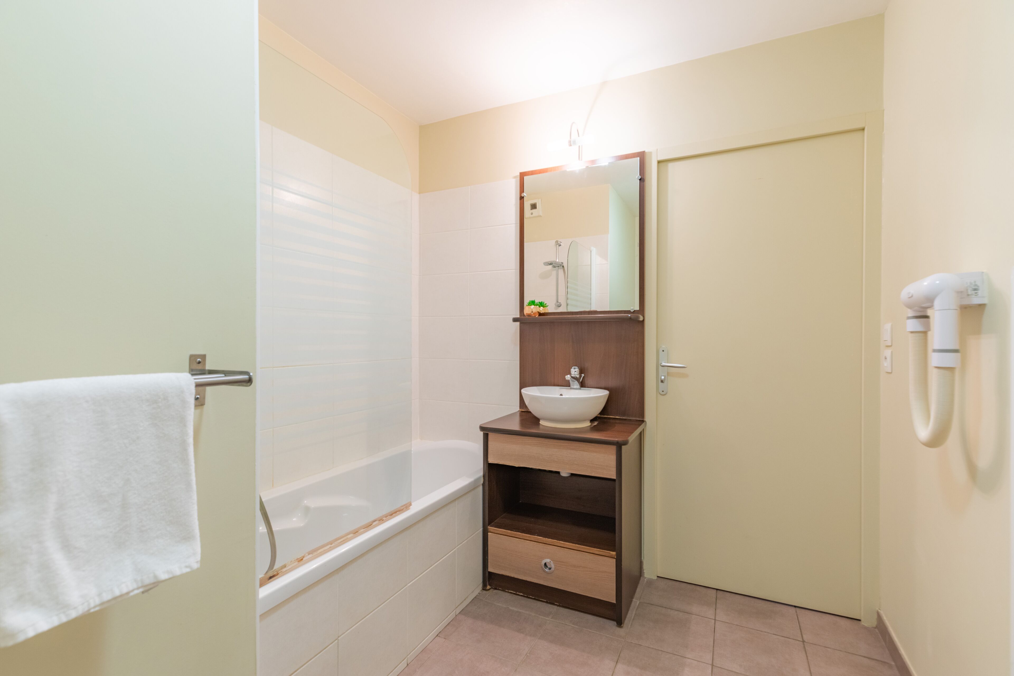 A bathroom with a bathtub, a sink with a mirror, and a towel rack.
