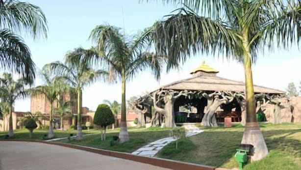 Un pavillon au toit de chaume, entouré de palmiers et bordé d’une pelouse bien entretenue.