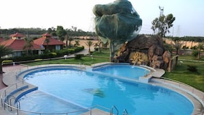 Une piscine de forme circulaire, entourée d’une terrasse dallée et de rampes en métal.