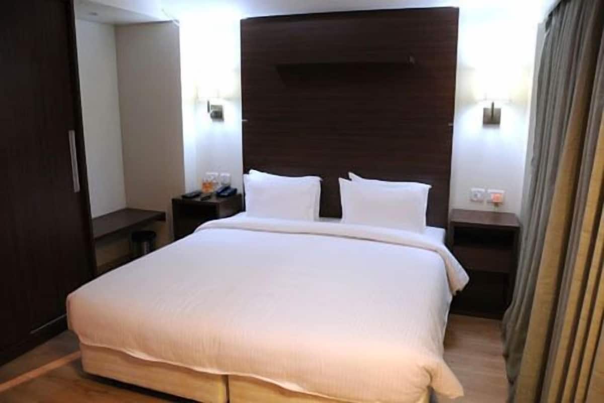 A large bed with white linens in a hotel room.