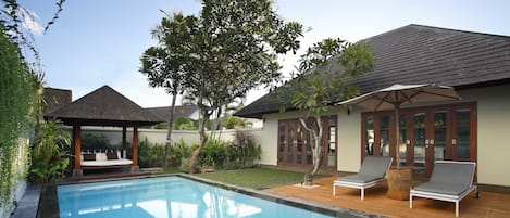 Una piscina al aire libre, sombrillas, sillones reclinables de piscina