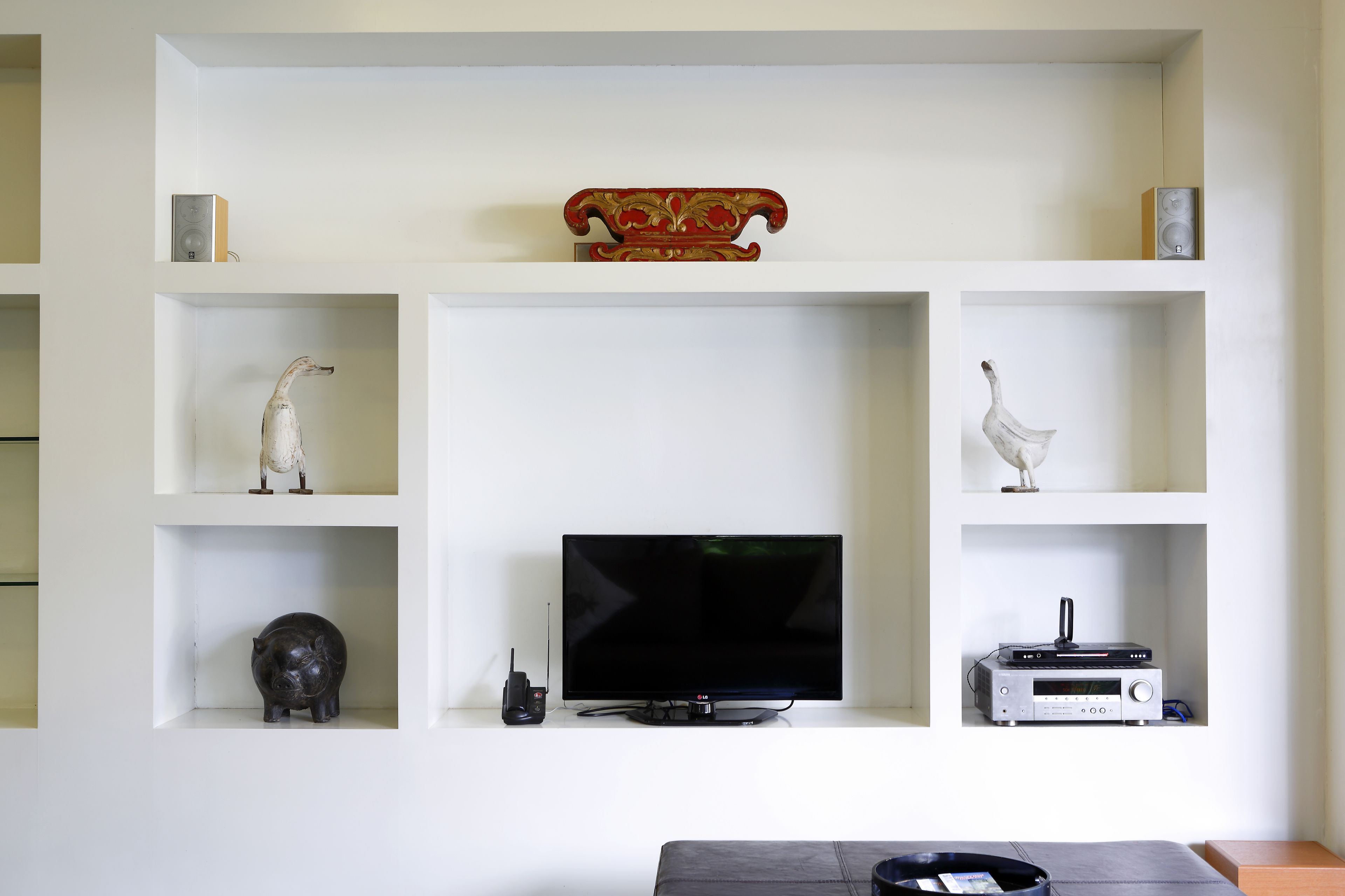 Un soggiorno con televisione a schermo piatto, impianto stereo e oggetti decorativi sugli scaffali.