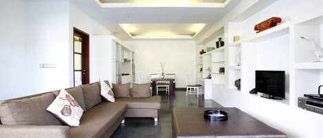 Una sala de estar moderna con un sofá, un reposapiés y un televisor de pantalla plana.