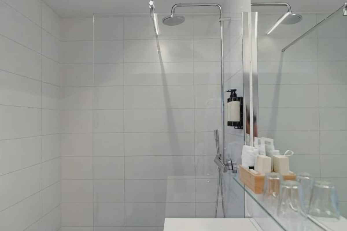 A modern bathroom with a glass shower enclosure, a white sink, and a mirror.