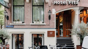 Fachada de hotel de ladrillo con una escalera que conduce a la entrada, y un cartel que dice "Hotel Fita".