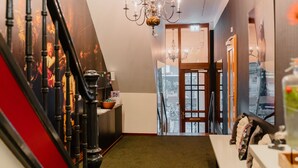 Un pasillo con escalera, un candelabro y vista al exterior.