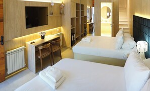Une chambre d’hôtel avec un lit, un bureau, une chaise, une télévision et une salle de bain visible à travers une porte ouverte.