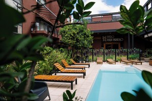 A poolside area with lounge chairs and a building with a sign reading "TEATRO PLAZA PARADISO". - Plaza Paradiso by Camberland (Chacras de Coria)