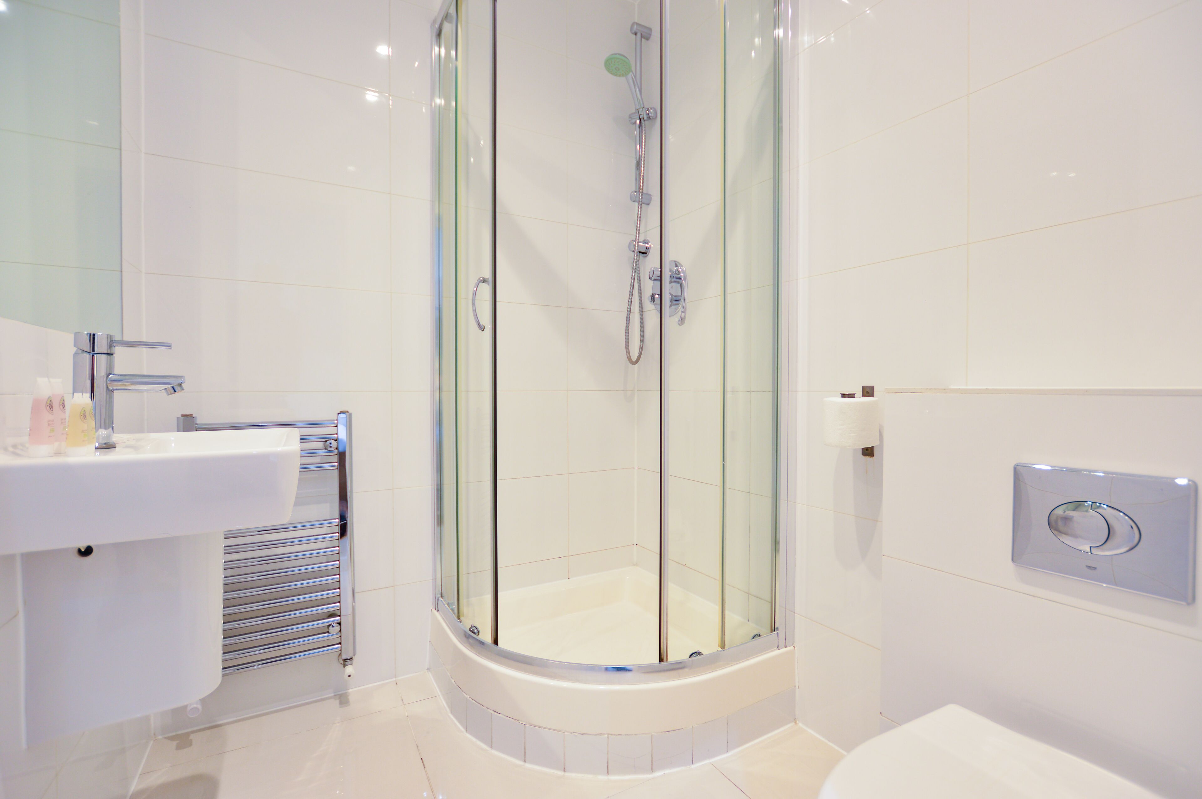 A modern bathroom with a glass-enclosed shower, a white sink, and a toilet.