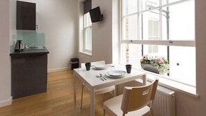 Une cuisine compacte comprenant une table et des chaises, un petit plan de travail et une fenêtre donnant sur l’extérieur.
