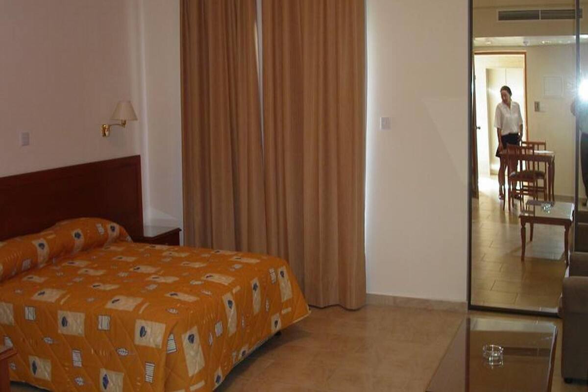 Una habitación de hotel con una cama, un espejo y vista a un comedor.