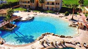 Ett semesterparadis med en stor pool, palmer och utsikt över havet.