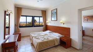 Habitación de hotel con dos camas, un escritorio y vista al mar.