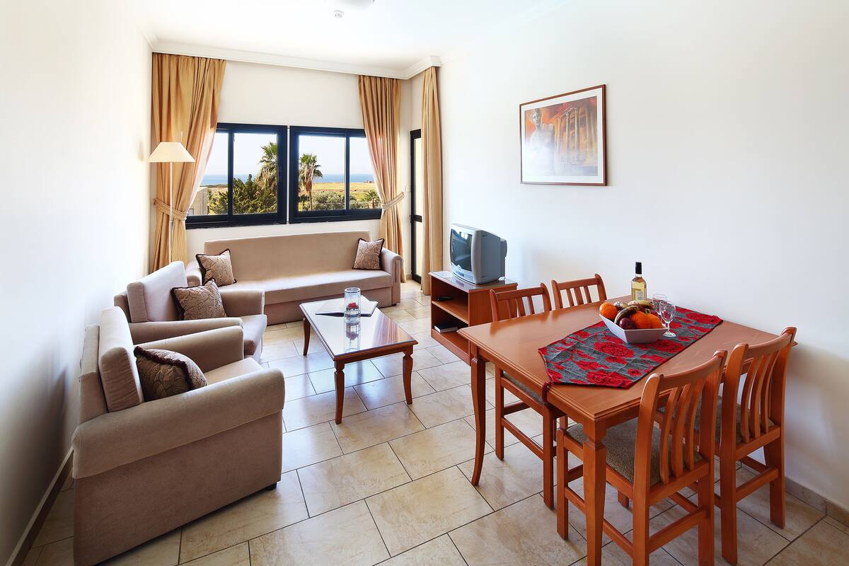 Una sala de estar con sofá, televisor, mesa de comedor y sillas.