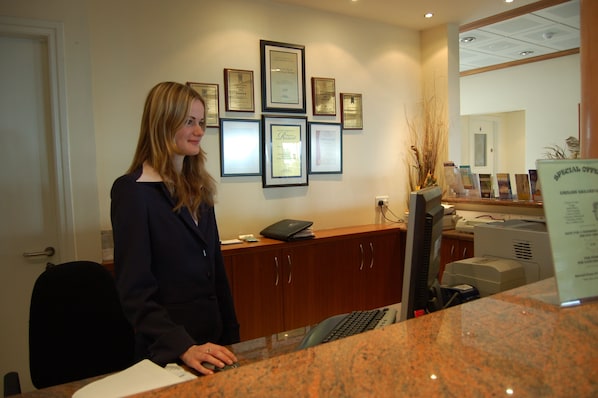A reception desk with framed certificates on the wall, a computer, and a printer.
