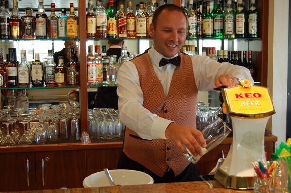 Un bartender sirviendo cerveza desde un grifo de marca en un vaso.