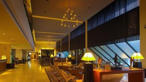 A spacious lobby with a high ceiling, a chandelier, and a large window providing natural light. There are seating areas with tables and lamps. - Batam View Beach Resort (Batam)