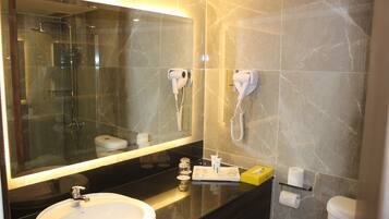 A modern bathroom with a large mirror, a sink, a shower, and two hair dryers mounted on the wall.