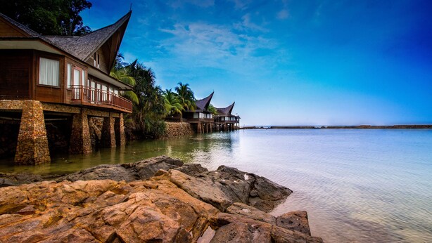 A beachfront resort with overwater bungalows supported by stone pillars, calm water, and clear skies. - Batam View Beach Resort (Batam)