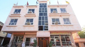 Un edificio de varios pisos con una entrada central, múltiples ventanas y banderas en el techo.