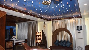A room with a bed, a seating area with cushions, a decorative ceiling with shells, and an air conditioning unit. - Golden Phoenix Hotel Boracay (Boracay Island)