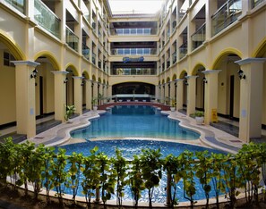 Un vestíbulo de hotel con una piscina central, varios balcones y un letrero del Hotel Golden Phoenix.