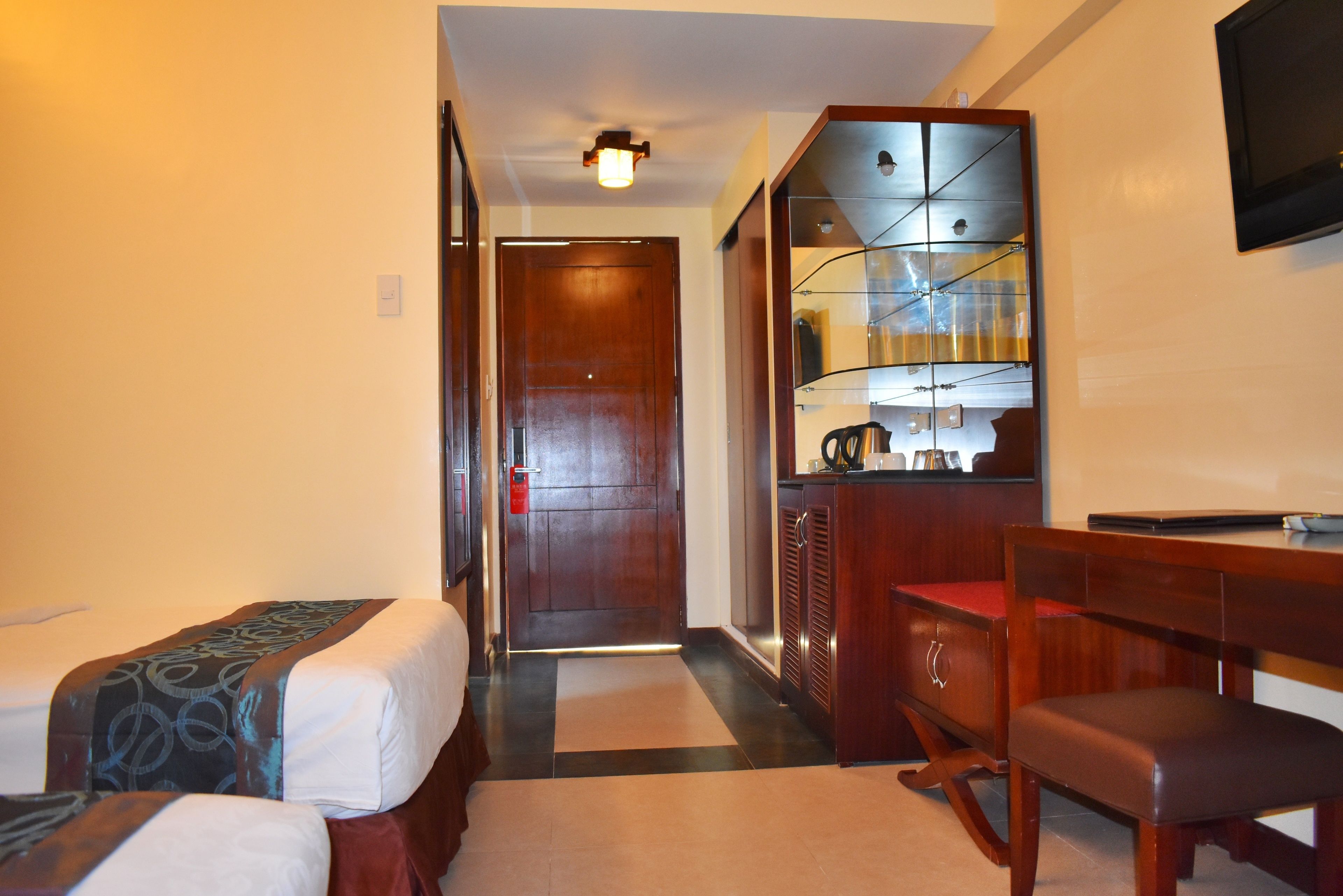 A hotel room with two beds, a desk, a chair, a mirror, and a television.