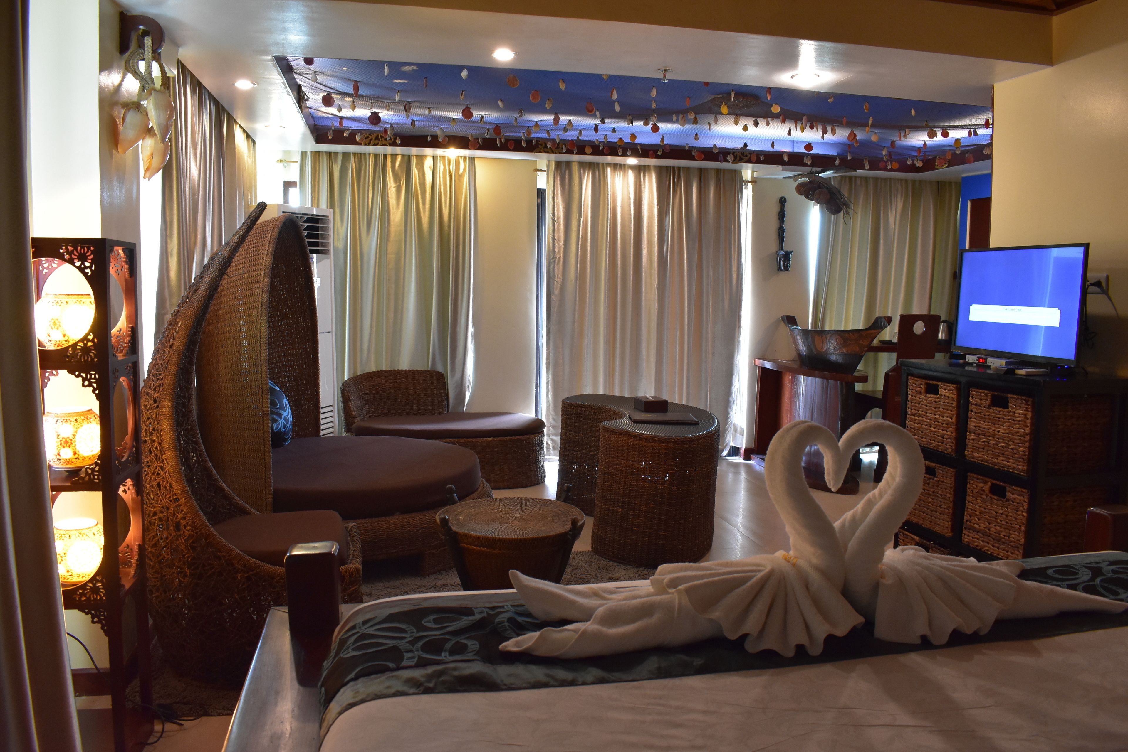 Una habitación de hotel con cama, sofá, sillón, televisión y una cisne decorativa.