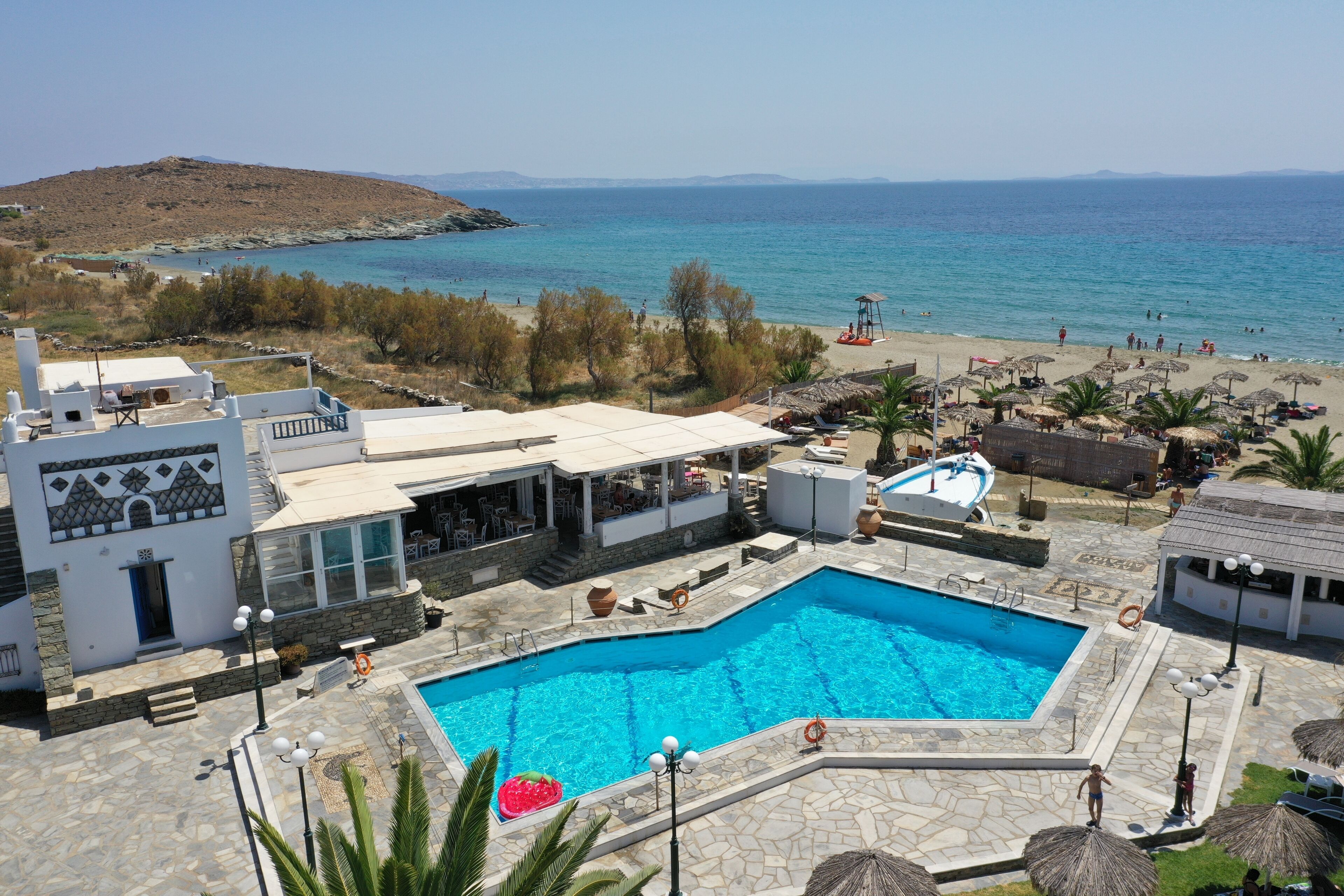 A resort with a swimming pool, beach, and clear blue sea.