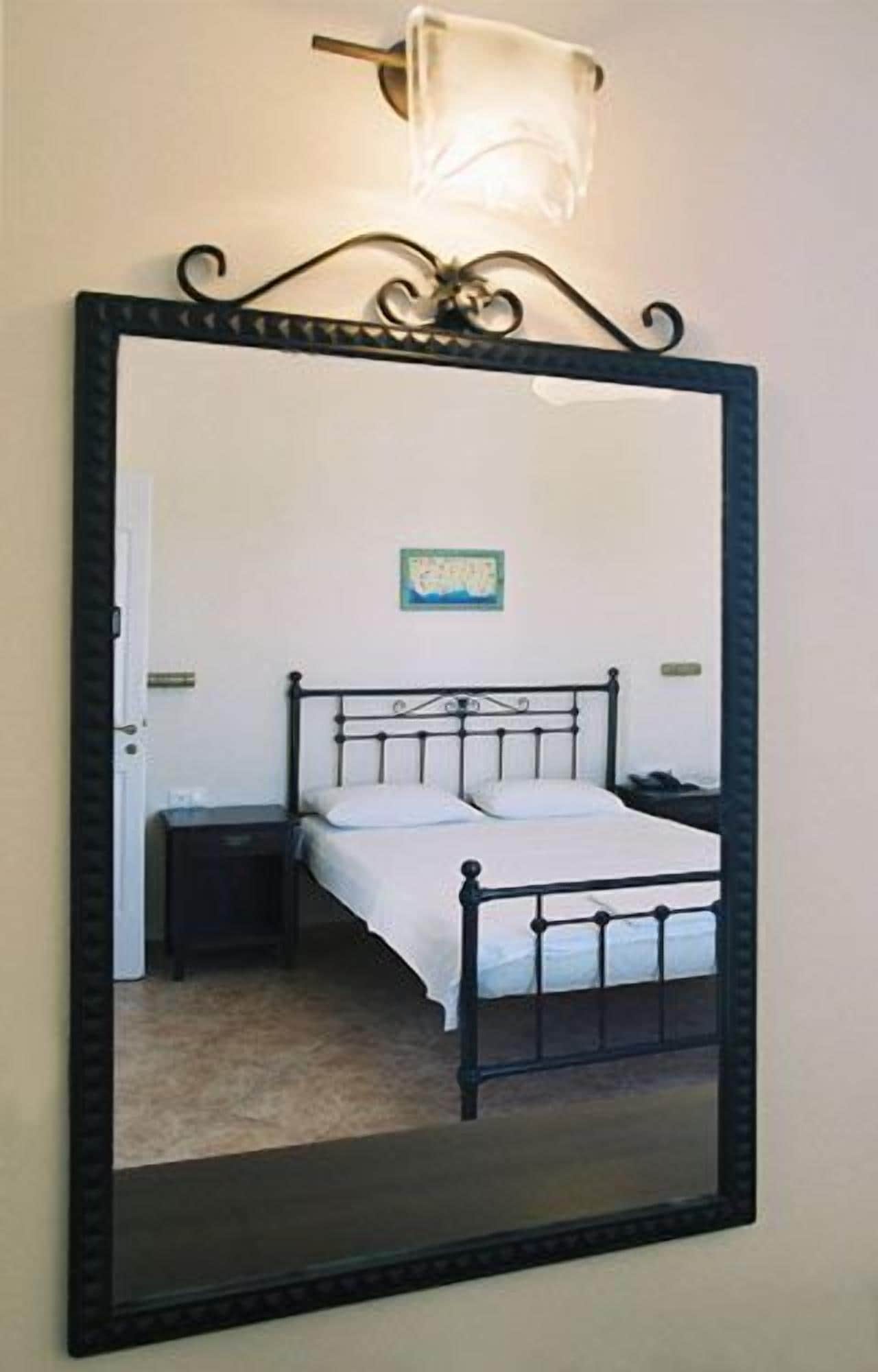 A bedroom with a bed, a nightstand, and a wall-mounted mirror.