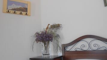 Un dormitorio con cabecera de madera, una mesita de noche con un florero y un cuadro en la pared.