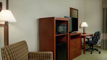 Habitación de hotel con sofá, escritorio con computadora, microondas y refrigerador.