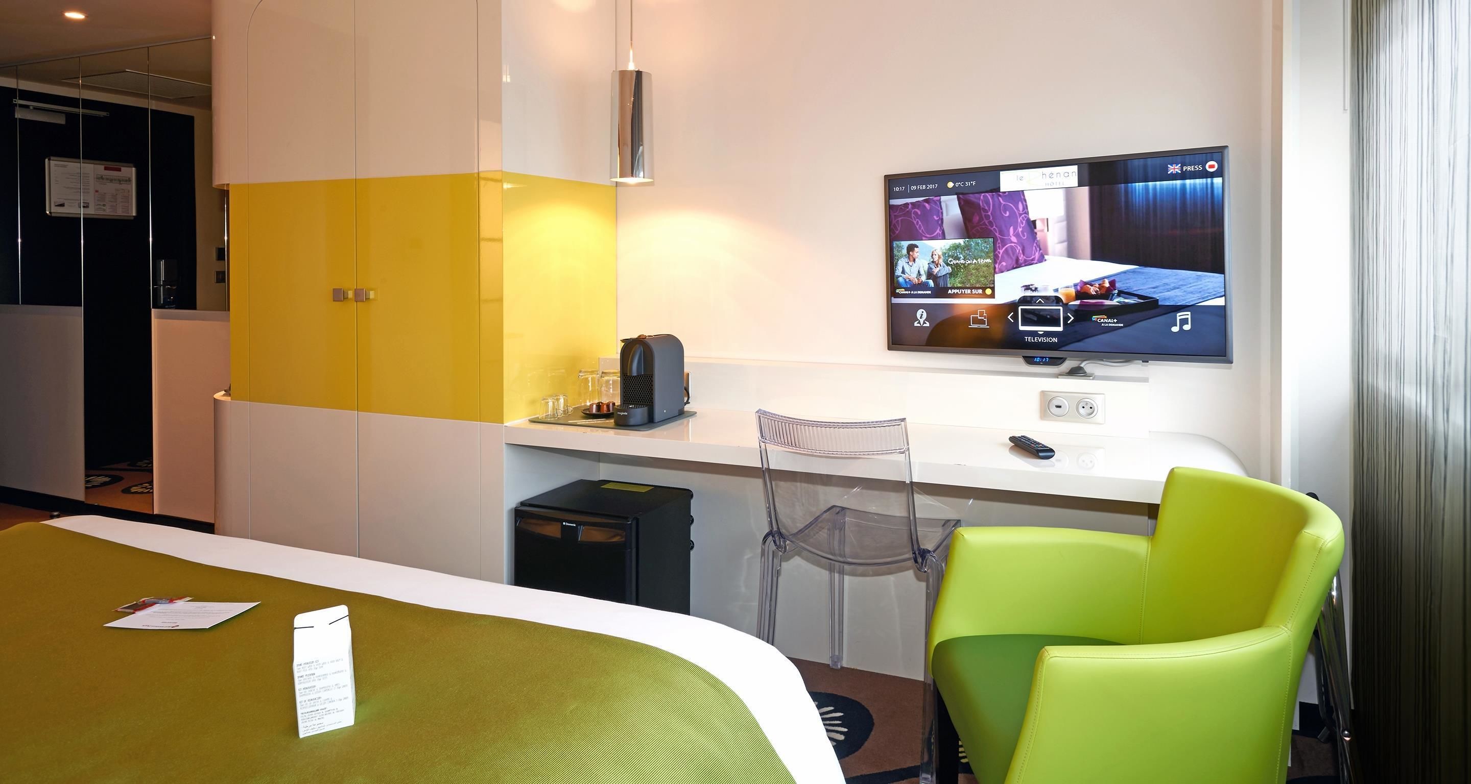A hotel room with a bed, a desk, a television, and a chair.
