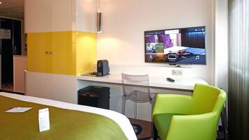 A hotel room with a bed, a desk, a television, and a chair.