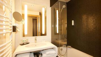 A modern bathroom with a large mirror, a sink, and a shower.