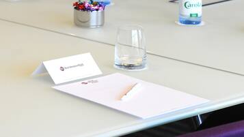 A table with a business card, a glass of water, and a pen.