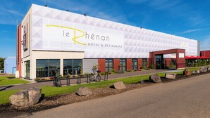 A modern hotel with a geometric facade, large windows, and a prominent logo.