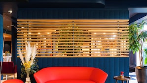 A modern interior with a red sofa, a wooden slatted wall, and a potted plant.