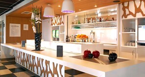Un área de bar moderna con una barra blanca, jarrones decorativos y una variedad de botellas y vasos.