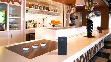 A modern bar area with shelves of bottles, glasses, and a bowl of oranges.