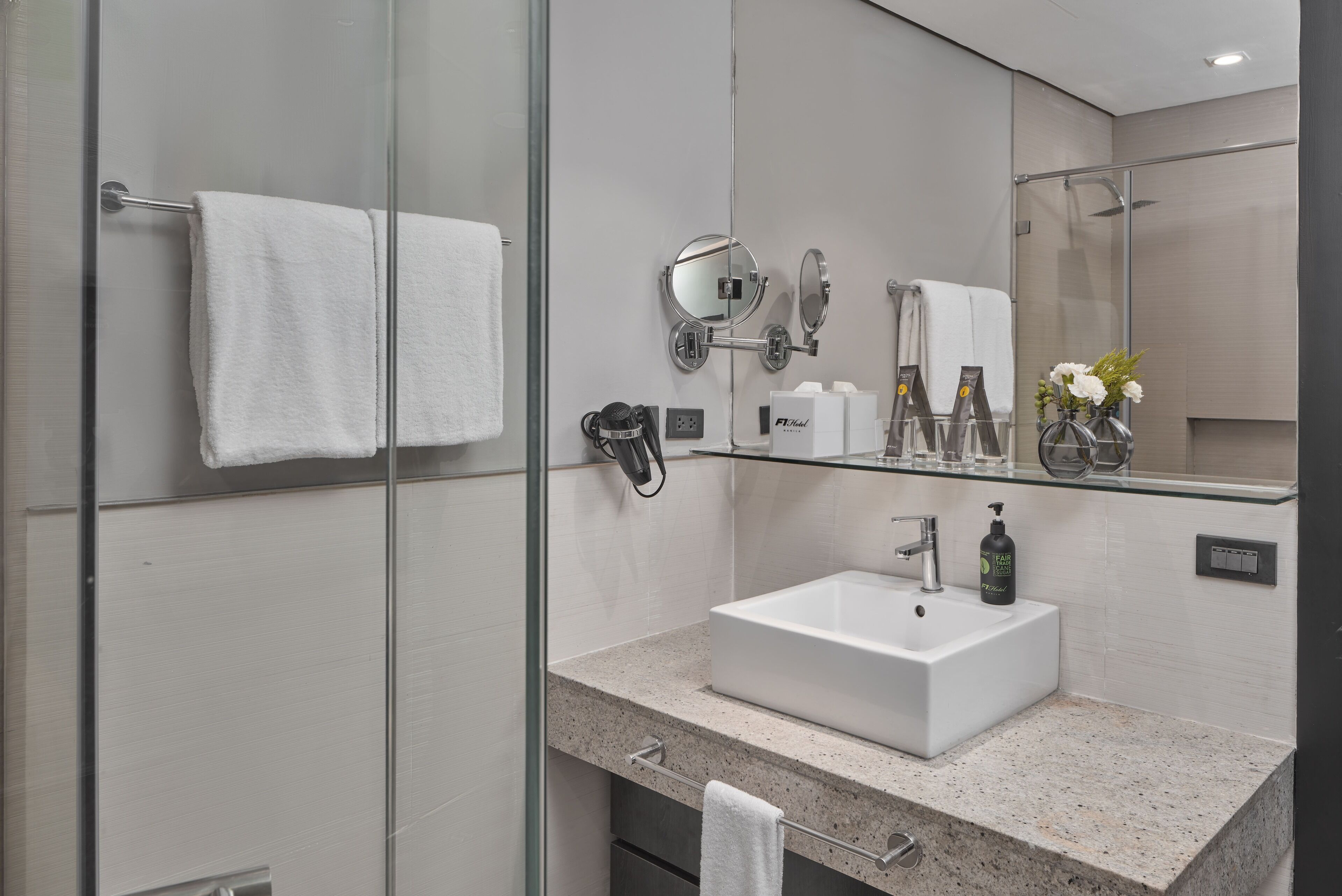 A modern bathroom with a glass shower enclosure, a white sink, and a large mirror.