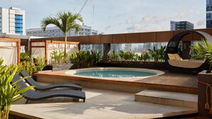 A rooftop pool area with lounge chairs, a hot tub, and potted plants. - F1 Hotel Manila (Taguig)