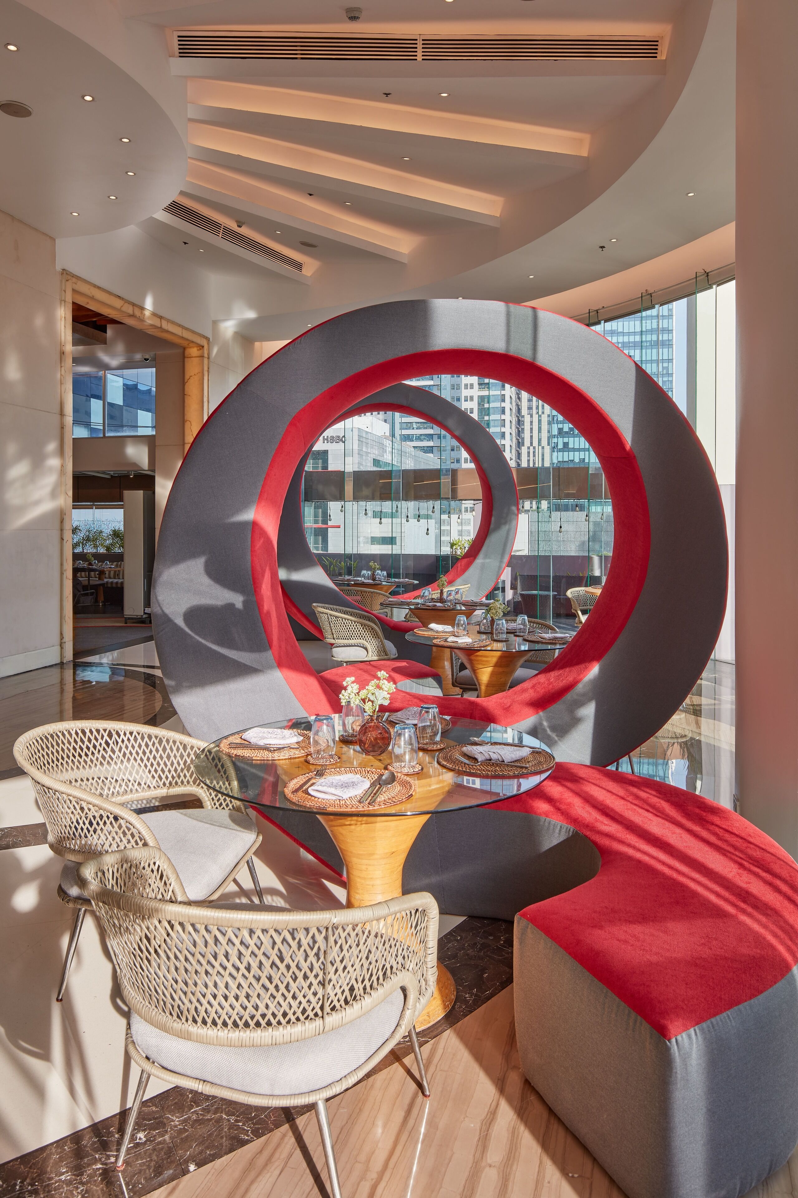 A modern dining area with a circular design element, wicker chairs, and a table set for dining.