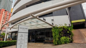 A tall, modern hotel with a curved facade, a reception sign, and a landscaped entrance area. - Mercure Belém Boulevard (Belém)