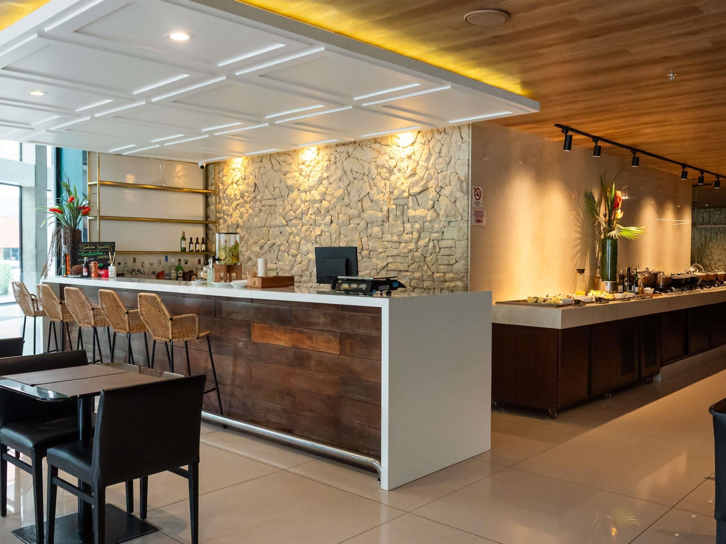 Uma área de bar moderna com parede de pedra, balcão e assentos.