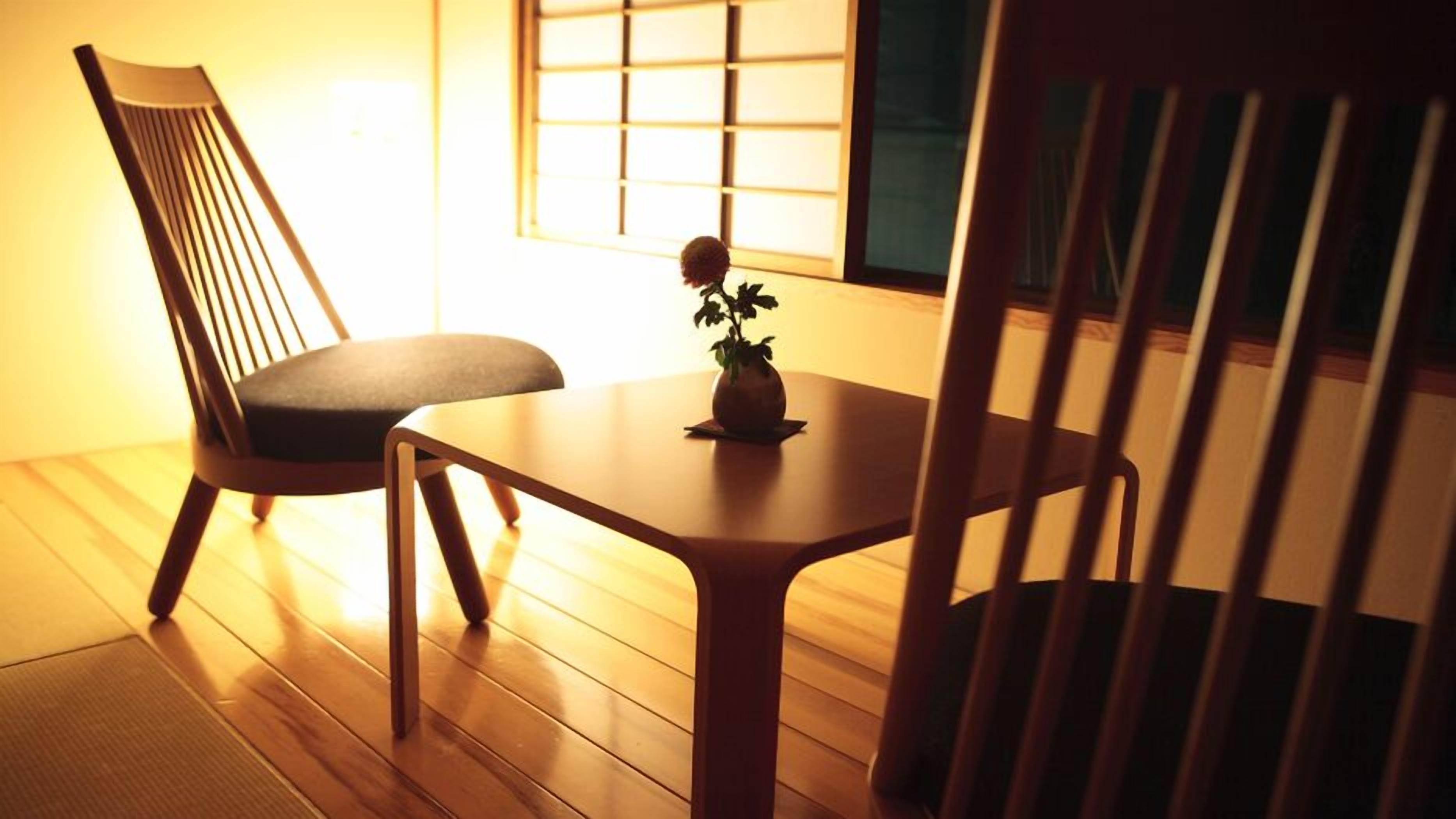 A wooden floor, a table with a small plant, and a chair.