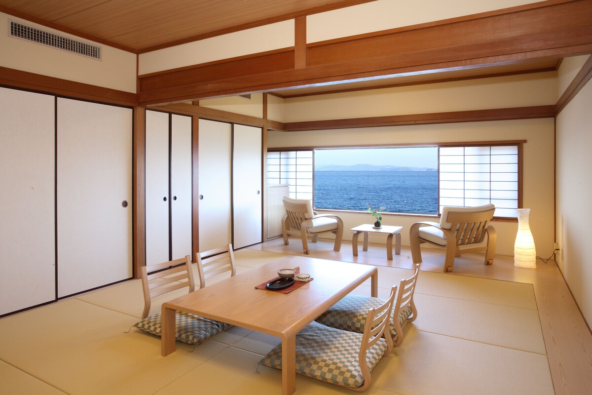 Una habitación tradicional japonesa con suelo de tatami, una mesa de madera baja y puertas correderas.
