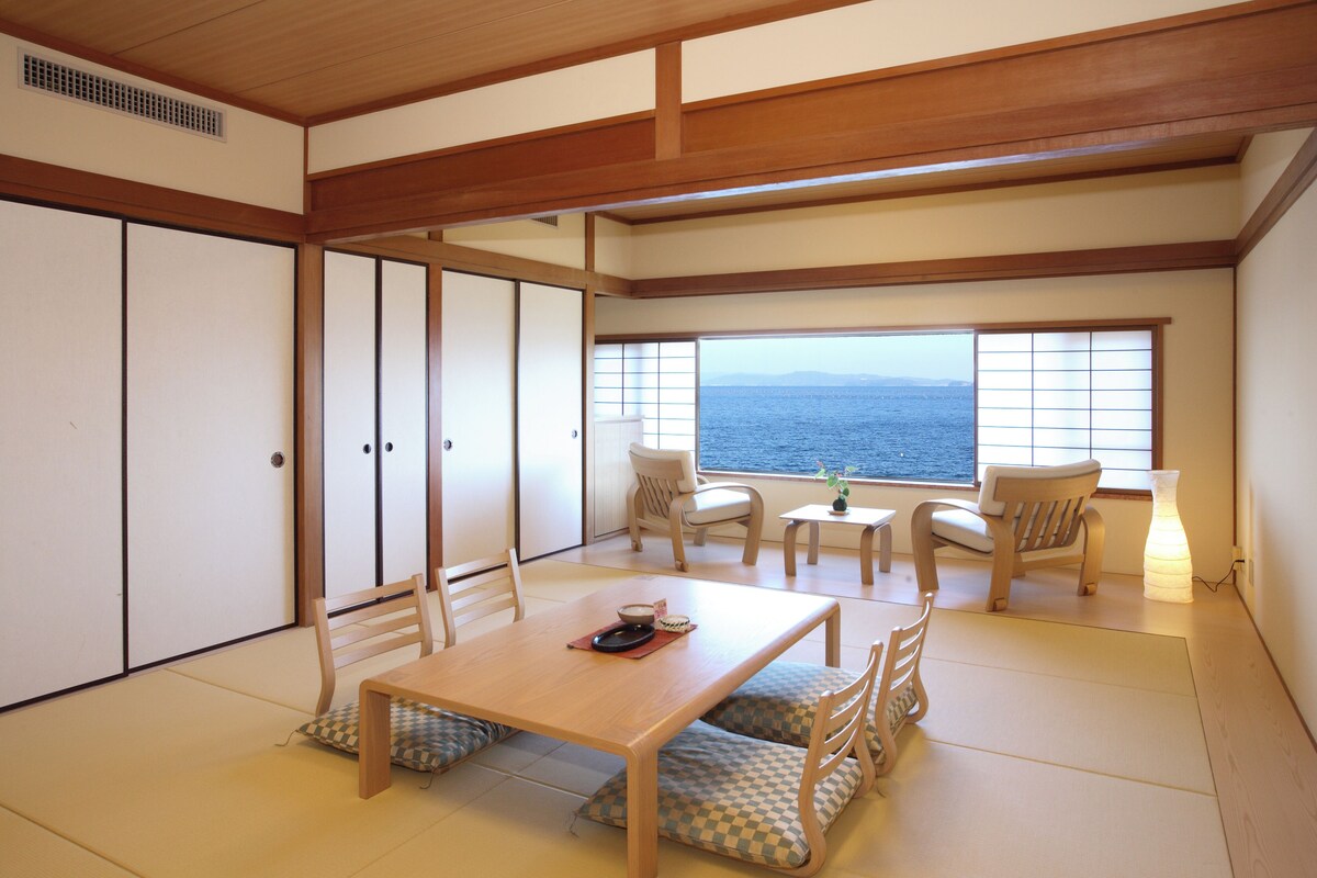 Una habitación tradicional japonesa con suelo de tatami, una mesa de madera baja y puertas correderas.